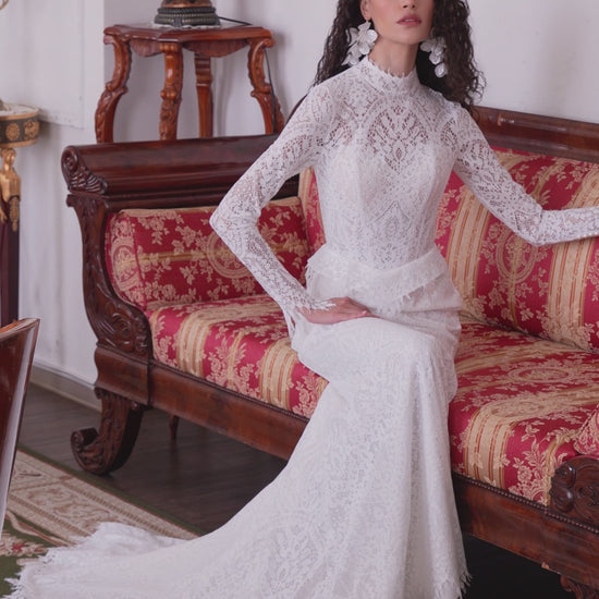 Long-sleeve high-neck lace mermaid wedding gown with open back and scalloped train.