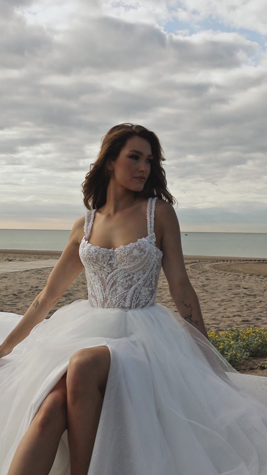 Sleeveless A-line bridal gown with boat neckline, lace bodice, wide straps, square back, glitter tulle slit skirt, and chapel train.