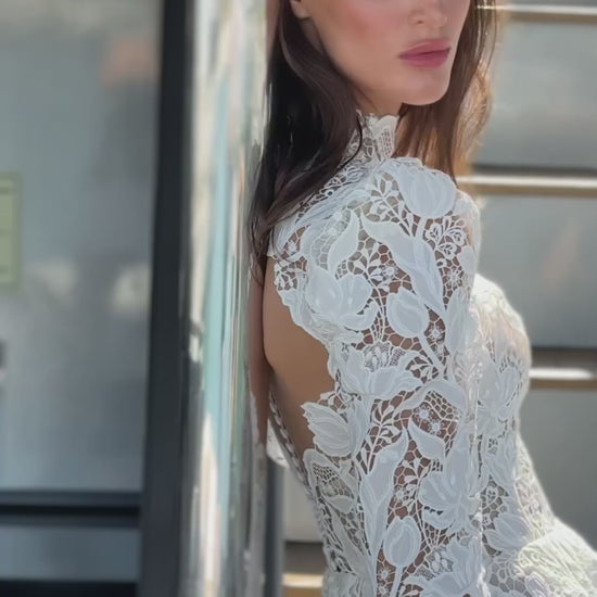 High-neck lace wedding gown with long puff sleeves, open back, and chapel-length train.