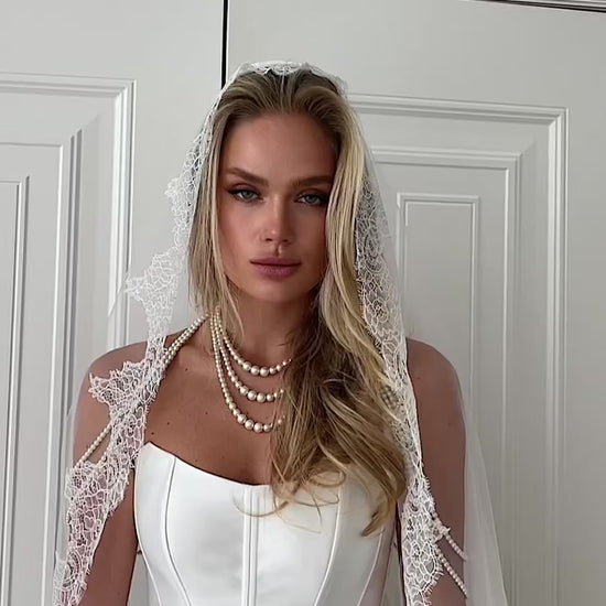 Video: close-up of a strapless corset with a lace-trimmed veil and pearl necklace