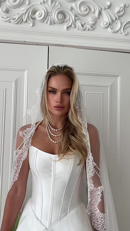 Video: close-up of a strapless corset with a lace-trimmed veil and pearl necklace