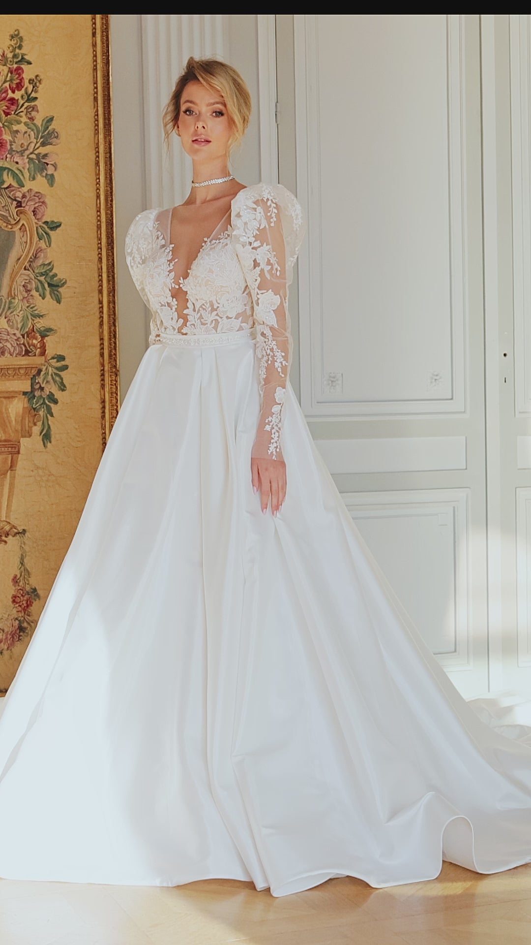  A-line wedding dress with puffy shoulder sleeves, V-shaped bodice, pleated skirt with pockets, embroidered belt, lace appliques, sequin details, and chapel train. Made of lace and taffeta mikado.