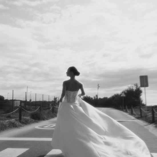 Bride in classic A-line atlas wedding gown with lace detail, V-cut neckline, drop waist, straight zip-closure back, and chapel train.