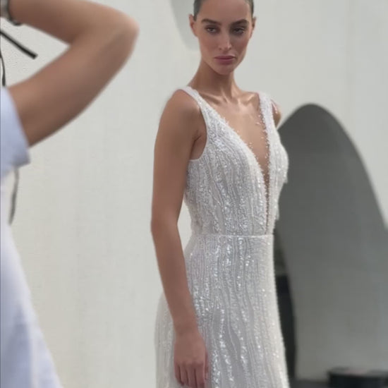 Radiant beaded A-line wedding gown with deep V neckline and open back, featuring a soft flowing tulle train.