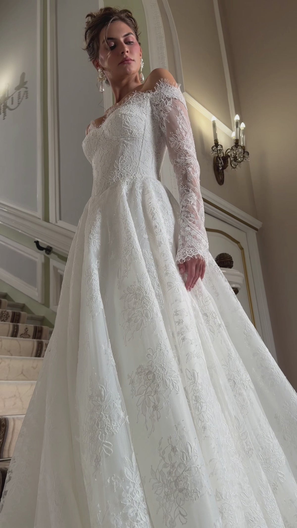 A-line floral lace wedding dress with an off-the-shoulder sweetheart corset, sheer long sleeves and a full skirt.