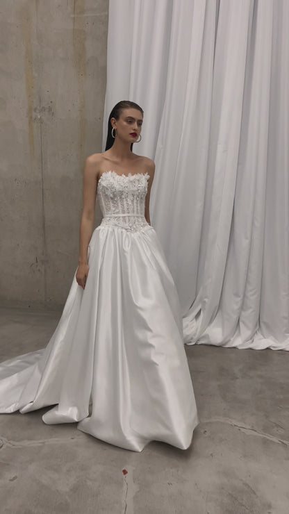 Sleeveless wedding dress with lace corset and floral details.