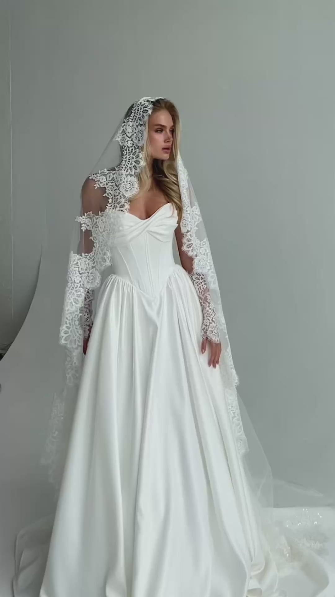 Video: bride in a satin A-line wedding dress with a long lace-trimmed veil