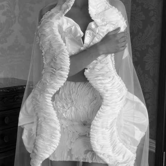 Mini wedding dress with a sweetheart corset bodice, sculptural ruffles and an optional sheer cape-veil.