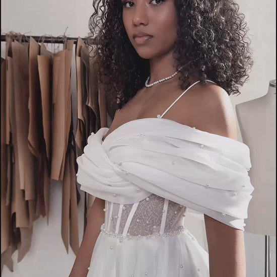 Organza A-line bridal gown with off-shoulder crossed draped neckline, spaghetti straps, pearl details, slit skirt, open back lace-up closure, and court train.