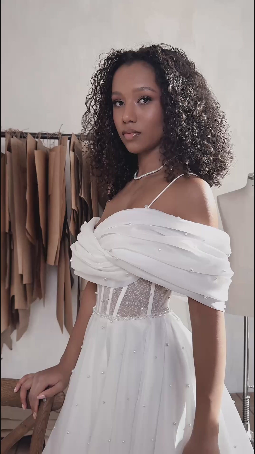 Organza A-line bridal gown with off-shoulder crossed draped neckline, spaghetti straps, pearl details, slit skirt, open back lace-up closure, and court train.