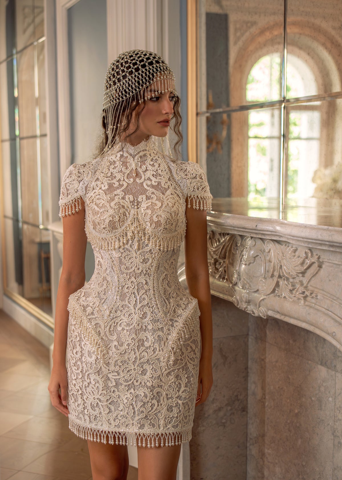 Lace mini wedding dress with high neck and cap sleeves – front view by a window