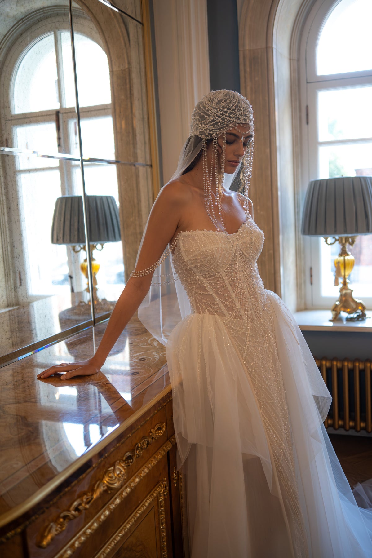 Beaded pearl corset wedding dress – side view leaning at a window with the tulle skirt
