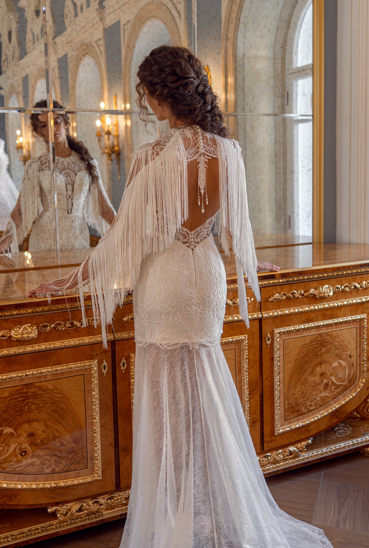 Lace wedding dress with fringe cape sleeves – back three-quarter view of the fringe and sheer skirt