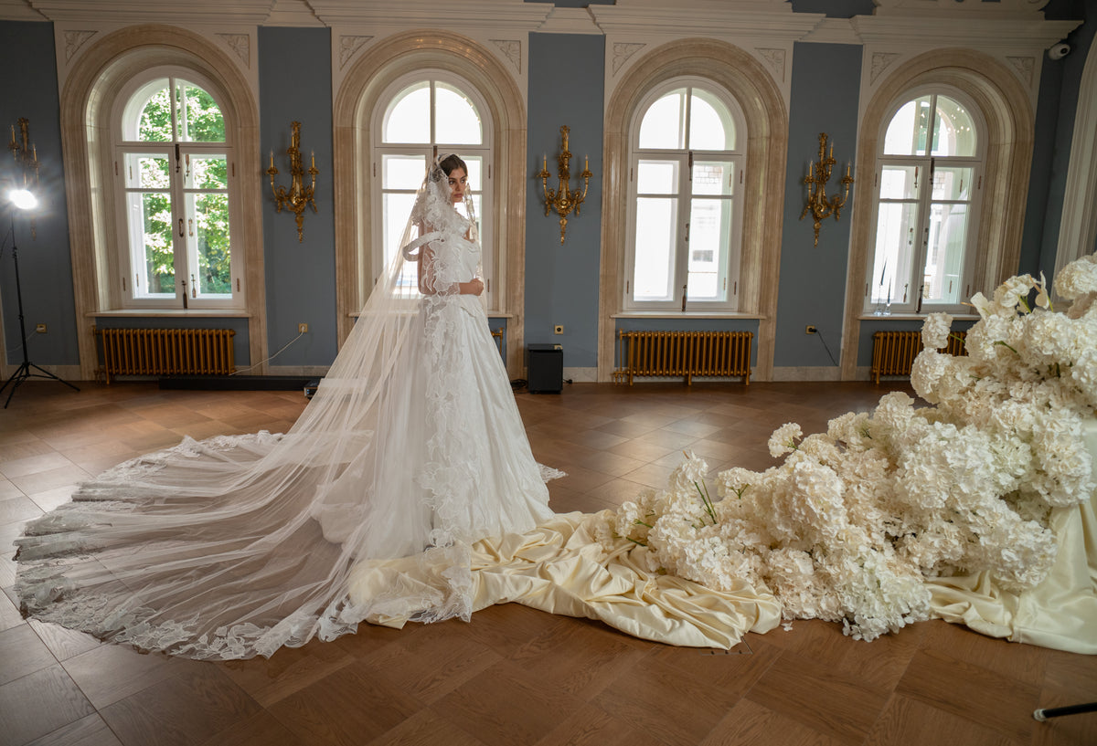 Taffeta ball gown wedding dress with off-shoulder draped corset – full-length view in a palace hall with the long train