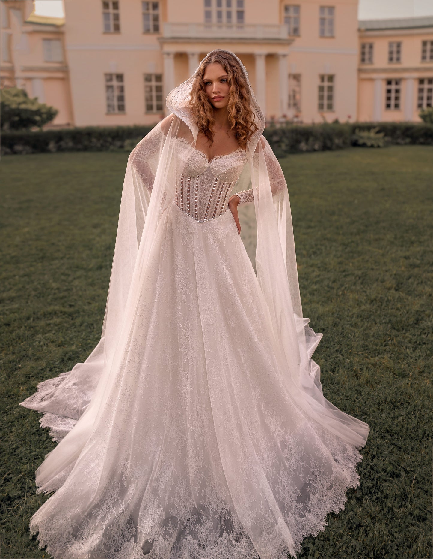 Romantic off-shoulder lace A-line wedding gown with long sleeves and corset bodice with cape