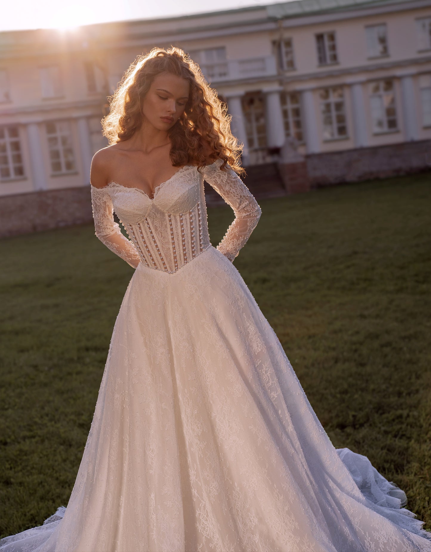 Romantic off-shoulder lace A-line wedding gown with long sleeves and corset bodice.