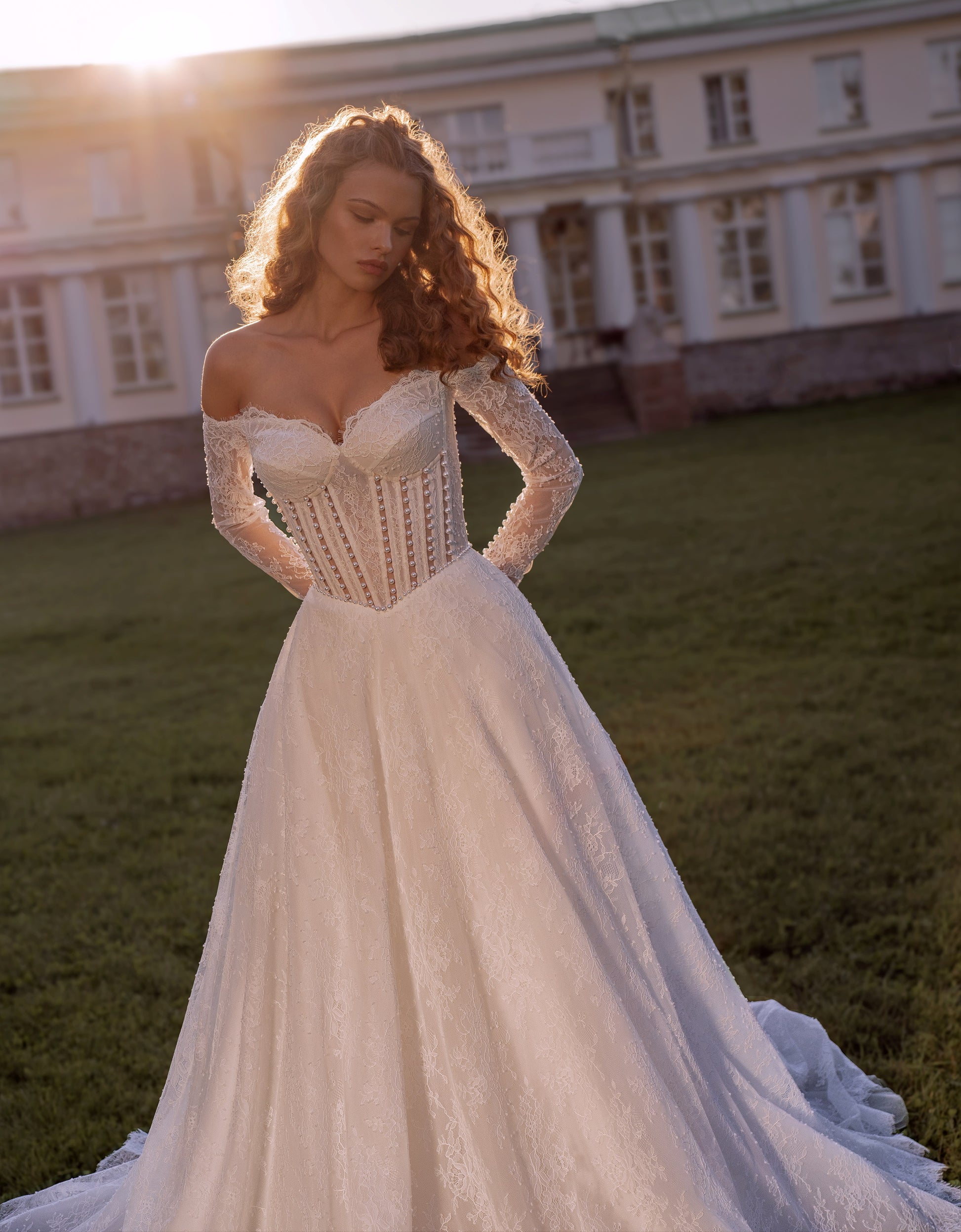 Romantic off-shoulder lace A-line wedding gown with long sleeves and corset bodice.