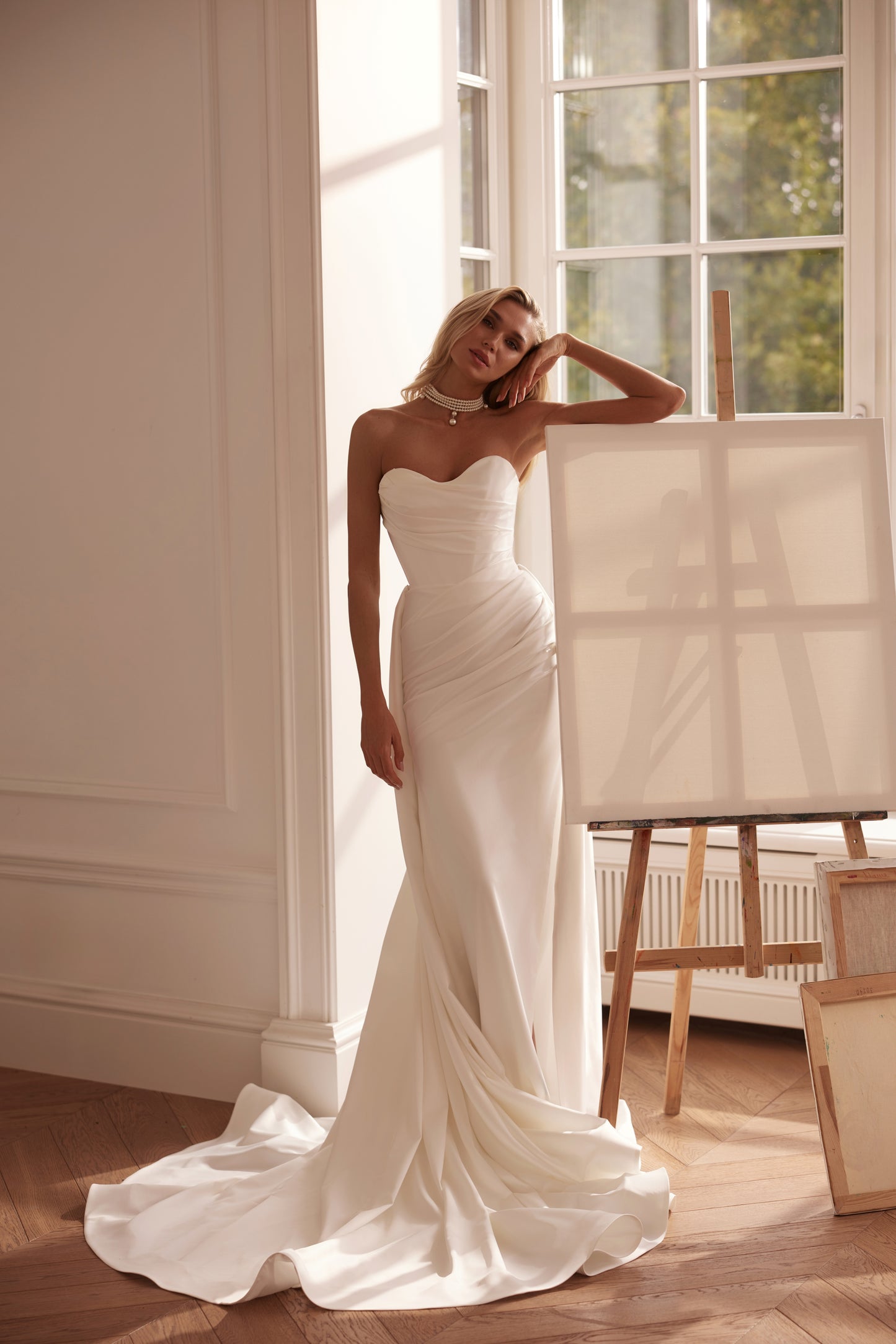 Strapless mermaid satin crepe wedding dress with draped bodice and flowing train.