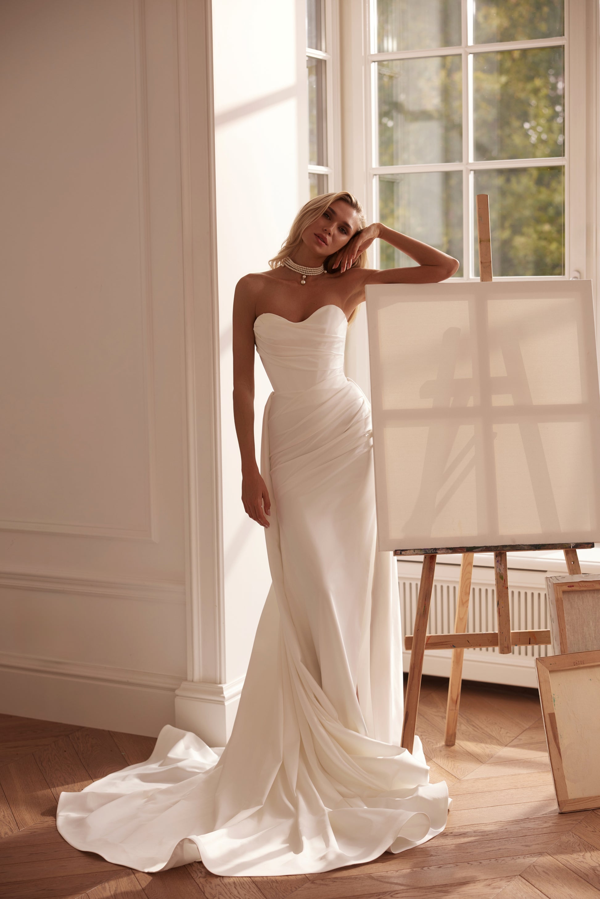 Strapless mermaid satin crepe wedding dress with draped bodice and flowing train.